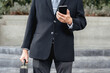 Businessman walking in city using a mobile phone while going to work.