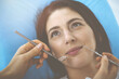 © rogerphoto - Smiling brunette woman being examined by dentist at dental clinic. Hands of a doctor holding dental instruments near patient's mouth. Healthy teeth and medicine concept
