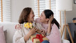 © ChayTee - Attractive beautiful asian middle age mum sit with grown up daughter give gift box and flower in family moment celebrate mother day. Overjoy bonding cheerful kid embrace relationship with retired mom.