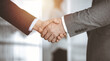 © rogerphoto - Business people standing and shaking hands in sunny office, close-up. Handshake and marketing