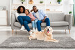Happy black family sitting in living room with dog