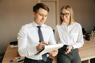 Businessmen and woman using tablet with documents in modern office. Company colleagues at the workplace. Business concept