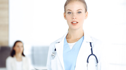 Woman - doctor standing in clinic. Physician at work, studio portrait. Medicine and health care concept