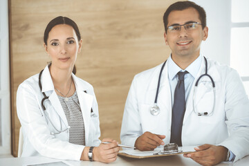 Two doctors discussing treatment problems while sitting at the desk in hospital office. Data in medicine and health care concept