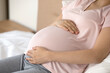 © fizkes - Crop close up of young Caucasian pregnant woman relax at home touch hold baby bump excited to meet kid child. Female resting enjoy easy healthy pregnancy time maternity leave. Motherhood concept.