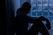 © Krisda - Silhouette depress woman sitting and hold smartphone in hand.