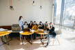 © Andrii - A group of girls in masks sit in a cafe and work on laptops. Teaching students.