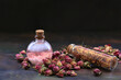 Small rose buds and rose oil in bottle on wooden table