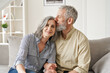 © insta_photos - Happy affectionate classy older mature couple bonding with eyes closed at home. Loving caring senior 50s husband embracing and kissing mid aged wife enjoying tender moment sitting on couch at home.