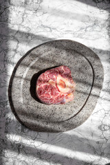 Wall Mural - Raw ossobuco on stone gray plate, sunlight immitation