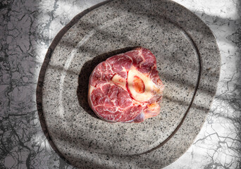 Wall Mural - Raw ossobuco on stone gray plate, sunlight immitation