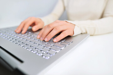 Woman sitting at the table and working with laptop. Closeup of business woman hand typing on laptop keyboard.