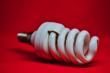 Sticker - Closeup shot of a spiral light bulb isolated on a red background