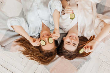 Wall Mural - two girls make homemade face and hair beauty masks. cucumbers for the freshness of the skin around t