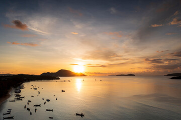 Aerial drone top view of sunrise over tropical beach with a lot of long tail boat. Beautiful early morning over calm sea and sky with many long tail boats