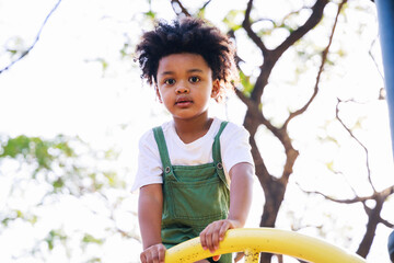 Wall Mural - Cute African American little kid boy funny while playing on the playground in the daytime in the spring season. Outdoor activity. Playing make-believe the concept. Outside education