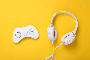 Wall Mural - White headphones with gamepad on yellow background. Creative gaming layout. Top view. Flat lay