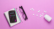 © splitov27 - flat lay medical composition. Economic analysis. Calculator with notepad, stethoscope and pills on pink pastel background. Top view