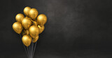 Fototapeta Boho - Gold balloons bunch on a black wall background. Horizontal banner.