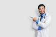 © Zubair - Doctor wearing uniform smiling while presenting and pointing isolated on blue background with copy space