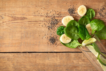 Wall Mural - Healthy food concept. Ingredients for cooking detox smoothie. Glass with spinach, banana, lime and chia seeds on wooden table top view, copy space