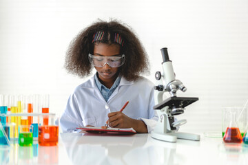 African american cute little girl student child learning research and doing a chemical experiment while making analyzing and mixing liquid in glass at science class on the table