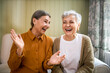 © shurkin_son - Elderly sisters watching comedy together indoors, laughing. Portrait of two beautiful Caucasian women relaxing at home, sitting on sofa, opening mouth wide opened, enjoying weekend, having fun
