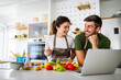 © NDABCREATIVITY - Young happy couple is enjoying and preparing healthy meal in their kitchen