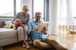 © NDABCREATIVITY - Beautiful happy mature couple is using a digital tablet, talking and smiling at home