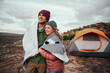 © StratfordProductions - Romantic man and woman wrapped in a blanket standing together outside tent on mountain looking at the beautiful nature