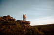 © StratfordProductions - Low angle view of young man and woman standing looking at beautiful view after hiking standing at mountain cliff peak