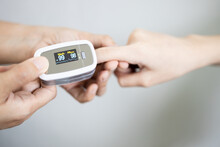 Fingertip pulse oximeter on the finger of young woman measuring heart rate (pulse) checking oxygen saturation (SpO2) level in the blood,diagnosis of Coronavirus or COVID-19 at home,health care concept