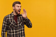 © timtimphoto - Studio shot of angry mad bearded man in plaid shirt looks aggressive looking and screaming loudly far away to the side isolated over yellow background