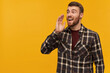 © timtimphoto - Happy attractive young bearded man in checkered shirt with hand near face shouting loudly and calling someone far away over yellow background