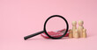 © nndanko - wooden figurines of little men family, magnifier and calculator on a pink background