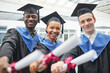 © Seventyfour - Diverse group of college graduates holding diploma certificates and smiling at camera indoors