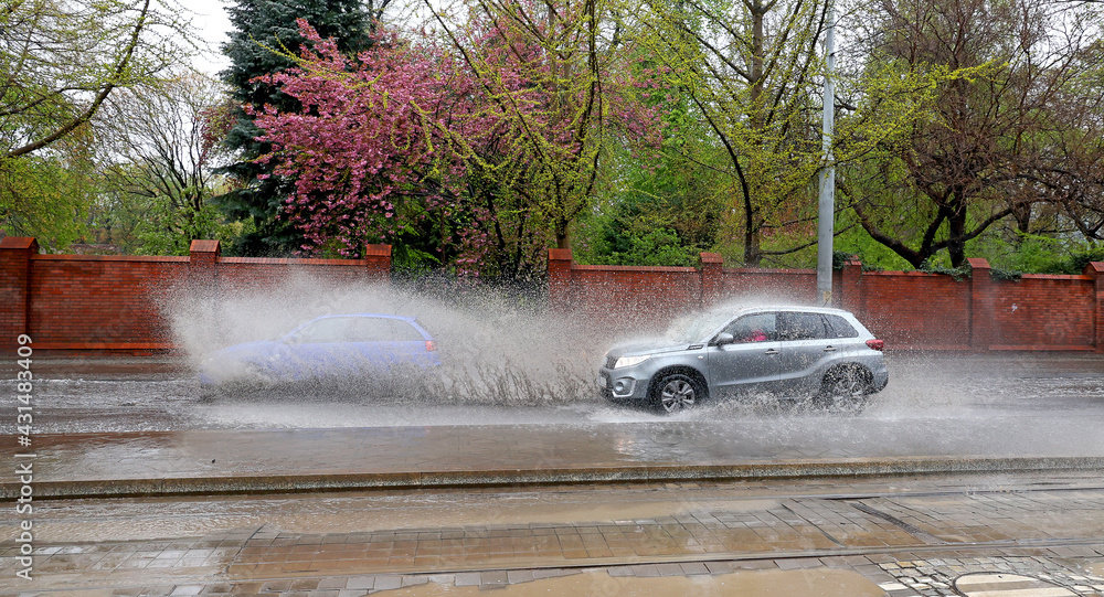 Samochód wpada w kałużę wody na jezdni powodująć rozbryzg.  - obrazy, fototapety, plakaty 