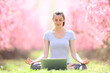 © PheelingsMedia - Yogi e-learning yoga with a laptop in a field