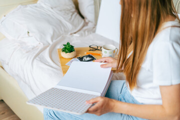 Top view of Cropped woman hands holding and watching a mockup family photo album. Mother sit on bed and watching mock up album with little baby son kid boy.