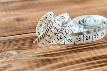 White measuring tape on a wooden background. Close-up.