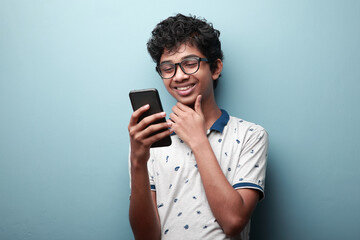 Smiling young boy of Indian origin looking at his mobile phone