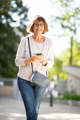Sticker - smiling older woman holding mobile phone outdoors