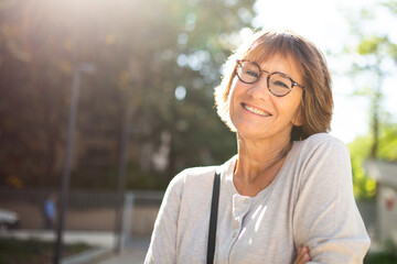 close up older woman with eyeglasses smiling outside
