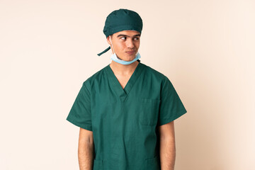 Wall Mural - Surgeon man in blue uniform over isolated background standing and looking to the side