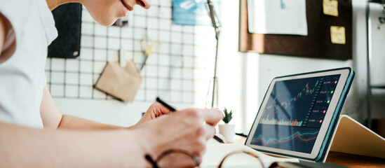 Woman working with investment stock market using tablet computer; analyzing trading data. Close-up