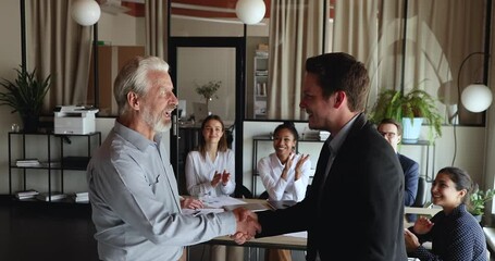 Poster - Smiling young ceo executive manager boss leader in formal wear shaking hands with older mature male colleagues, thanking for good job, showing respect and recognition, congratulating with retirement.