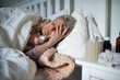 © Halfpoint - Sick senior woman sleeping in bed at home, cold and flu concept.