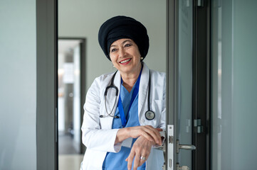 Portrait of senior woman doctor standing in hospital, looking at camera.