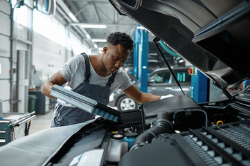 Wall Mural - Male worker changes oil in engine, car service