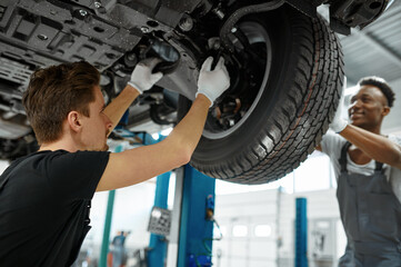 Wall Mural - Two male workers fixes wheel, car service